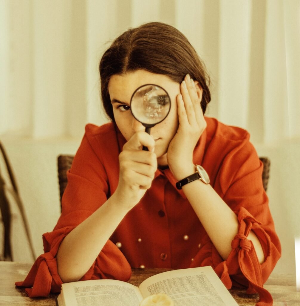 Woman looking at the camera through a magnifying glass